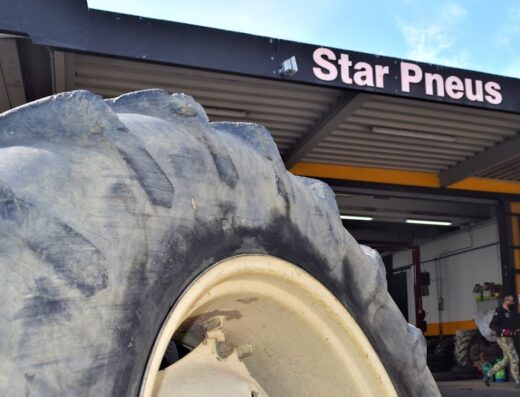Primo piano di un pneumatico agricolo davanti all'officina Star Pneus BestDrive, che offre servizi di vendita e riparazione pneumatici.