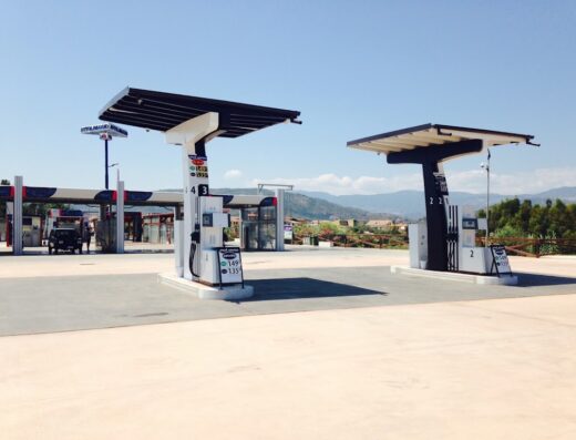 Stazione di servizio carburante Easy Fuel con pompe di benzina per moto e auto, cartelli prezzi carburante benzinai visibili e cielo sereno.