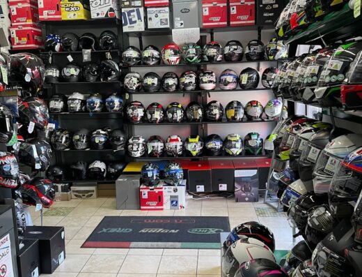 Interno di negozio Stile Moto con esposizione di caschi da moto di varie marche, modelli e colori, accessori per motociclisti e scatole di imballaggio a scaffale