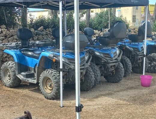 File di quad blu sotto un gazebo con marchio Yuasa Battery e SIFAM.it, accessori e servizi per motociclisti e viaggi avventura