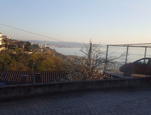 Vista panoramica dalla Strada del Friuli 230 con mare, città e vegetazione. Panorami mozzafiato per motociclisti in viaggio.