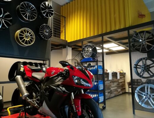 Interno di Sturlagomme: moto rossa in primo piano, esposizione di cerchi e pneumatici, officina specializzata per moto
