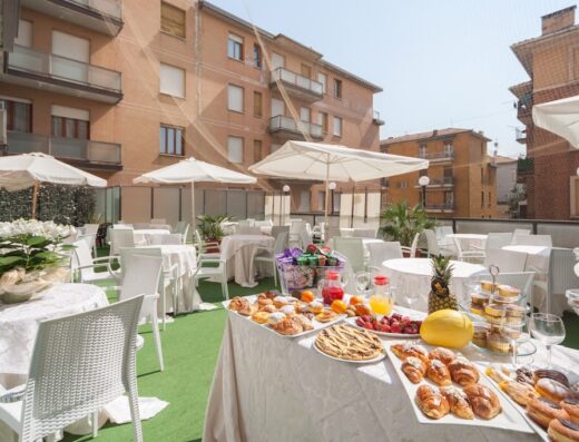 Buffet all'aperto all'Hotel Suite Elite con tavoli apparecchiati, ampia scelta di dolci, frutta fresca, succhi di frutta e decorazioni floreali.