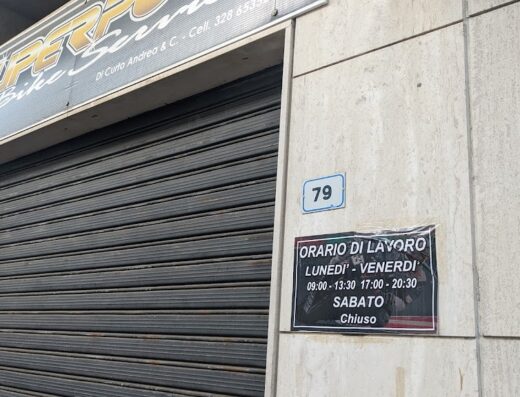 Superpole Bike Service storefront with closed shutters and business hours posted, indicating motorcycle maintenance and repair services are available. The shop number is 79.