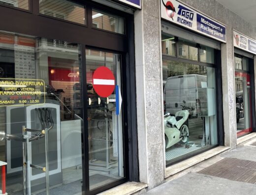 Tago Ricambi store front featuring Enduro Motard and motorcycle accessories, displaying a white motorcycle in the window. Motorcycle parts and service marketplace.