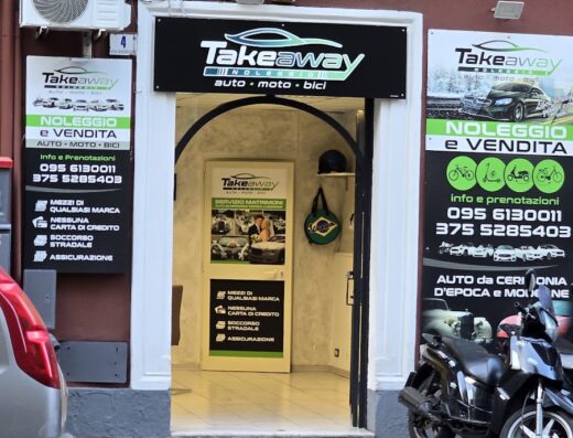 Foto della facciata di Takeaway, negozio di noleggio auto, moto e bici a Catania, con scooter parcheggiato davanti e insegne ben visibili. Servizi di soccorso stradale e assicurazione disponibili.