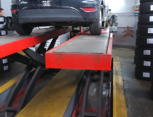 Auto nera su ponte elevatore per cambio gomme e manutenzione presso Td Gomme, officina specializzata in servizi pneumatici e assetto ruote.