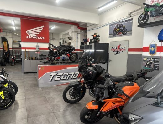 Interno di Tecnomoto, officina specializzata in riparazione e vendita moto, con diverse motociclette esposte e in riparazione.