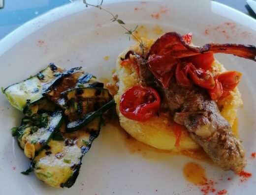 Piatto gourmet con polenta, carne, pomodorini e zucchine grigliate, servito presso Tenuta Mirco Agriturismo.