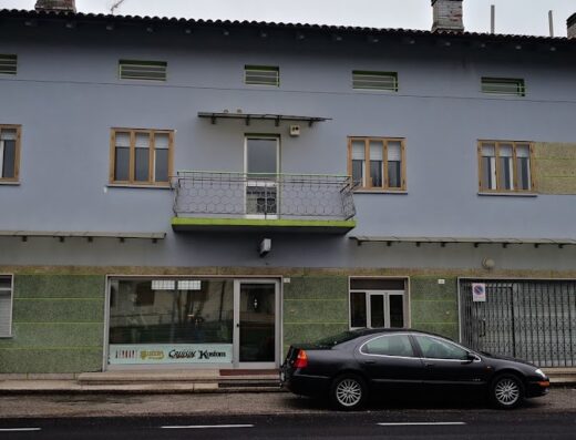 Terre di Moto srl storefront featuring a gray building facade with green accents, a black car parked in front, and visible signage, showcasing motorcycle accessories and services.
