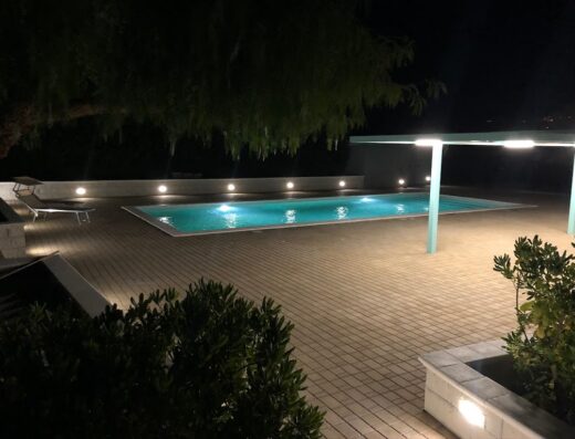 Piscina illuminata di notte al Terre Iblee Resort, con area relax e vegetazione circostante. Perfetta per vacanze e relax.