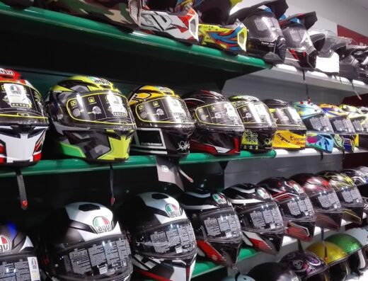 Vetrina di un negozio con diversi caschi da moto AGV di vari colori e modelli esposti su scaffali, accessori per motociclisti e bikers