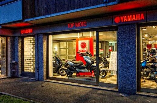 Top Moto, concessionario ufficiale Yamaha: esposizione di moto, scooter e caschi nel negozio con insegna luminosa Yamaha.