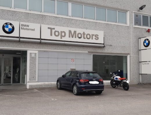Top Motors BMW Motorrad Ancona dealership featuring BMW motorcycles parked outside, a blue car, and the BMW Motorrad logo signage.