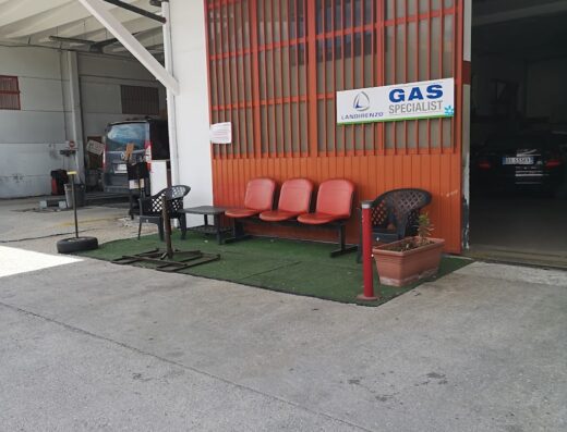 Foto dell'esterno di Top Service Cerrone Mario, un'officina specializzata in impianti a gas Landirenzo per auto, con area di attesa e ingresso all'officina.
