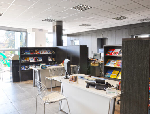 Interno dell'agenzia viaggi e crociere Torelli Tours 2, con scrivanie, computer, cataloghi di viaggi e brochure informative a disposizione dei clienti.