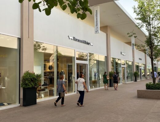 Torino Outlet Village: Shoppers stroll past storefronts, including Harmont & Blaine, enjoying a day of retail travel and accessory shopping.