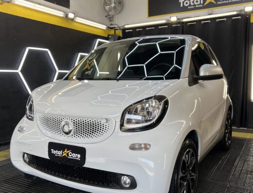 Smart bianca in un ambiente di detailing auto con illuminazione moderna, pronta per servizi di cura e manutenzione Total Care.