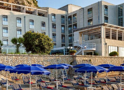 Towers Hotel Stabiae Sorrento Coast vista esterna con spiaggia privata, ombrelloni blu e lettini. Ideale per vacanze e relax sulla costa.