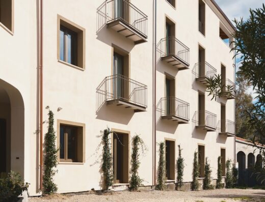 Vista esterna dell'hotel e spa Tramas, che mostra finestre e balconi in un edificio color crema con vegetazione rampicante.