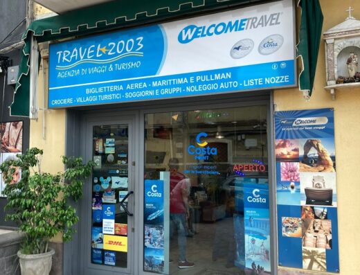 Foto dell'agenzia di viaggi Travel 2003 di Mirabella Vanessa, con insegna, vetrina con offerte crociere Costa e servizi turistici come biglietteria aerea e noleggio auto.