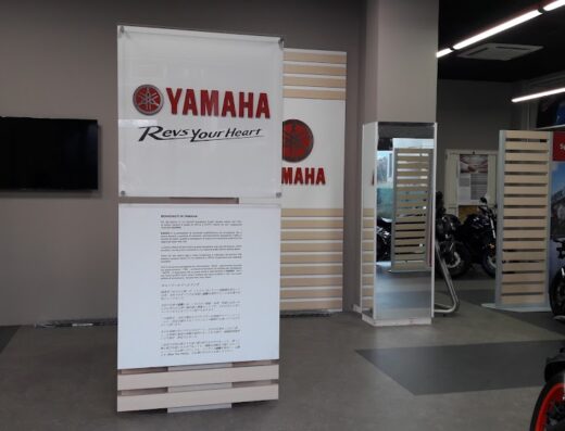 Interno del negozio Trimboli Moto a Siderno, con espositori Yamaha e diverse moto in vendita. Servizi e accessori per motociclisti e appassionati di viaggi su due ruote.