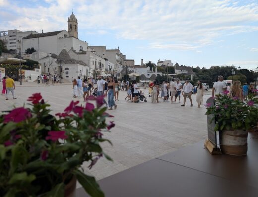Piazza affollata ad Alberobello con trulli sullo sfondo, Puglia. Persone passeggiano e godono della vista. Trullo Malvasia Anti' Charme & Relax.