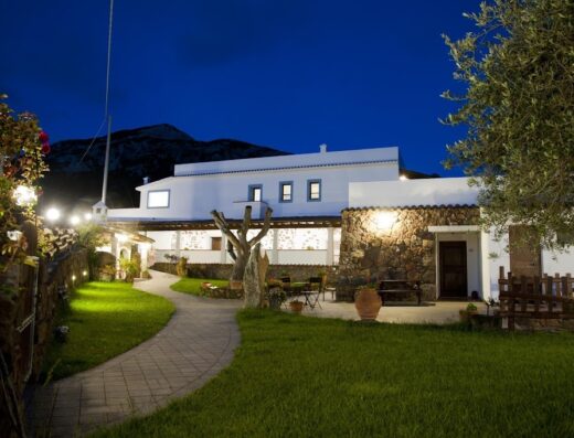 La facciata illuminata di sera del Turismo Rurale Belvedere Pradonos, con vialetto, giardino curato e dettagli rustici in pietra.