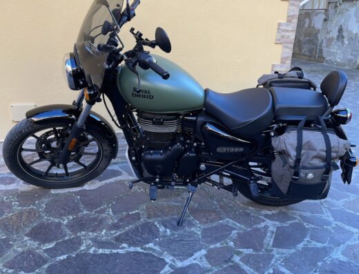 Moto Royal Enfield Meteor 350 verde oliva accessoriata per il turismo, con parabrezza, borse laterali e sella confort, ideale per viaggi e avventure su strada.