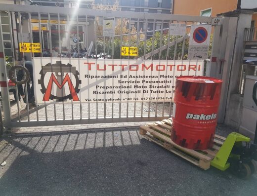Ingresso di TuttoMotori Bolzano, officina specializzata in riparazioni moto, assistenza, servizio pneumatici e preparazione moto stradali. Barile di olio Pakelo in primo piano.