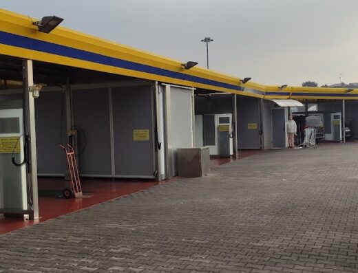 Foto del Twister Car Wash SRL, un autolavaggio self-service con box individuali per la pulizia di auto e moto; struttura con tetto giallo e blu.