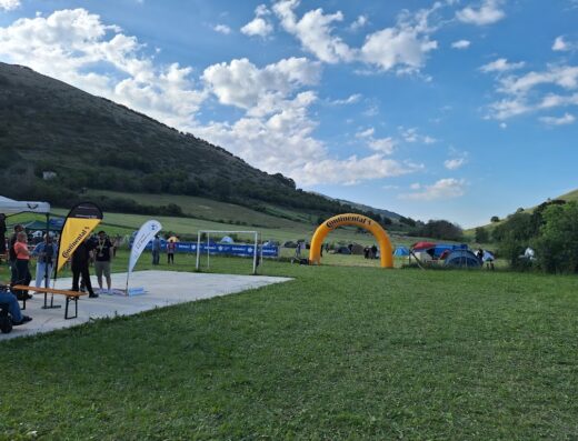 Esperienza Umbria Raid: campeggio con tende e arco gonfiabile Continental in un paesaggio collinare durante un evento motociclistico.