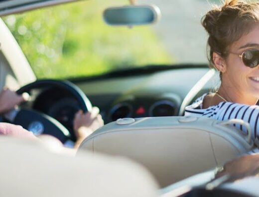 Una coppia sorridente guida una cabriolet, ideale per il noleggio auto per vacanze e viaggi con Unicar Rent.