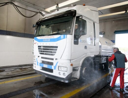 Autolavaggio Va.ma.r. srl: camion Iveco Stralis bianco in fase di lavaggio con idropulitrice da parte di un operatore.