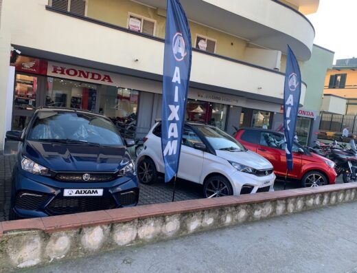 Valentino Racing concessionaria Honda e Aixam a Caserta, con esposizione di Aixam Minicar nuove, moto Honda e bandiere promozionali.