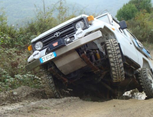 Fuoristrada bianco Toyota in azione su terreno sterrato in Valle d'Aosta, accessorio motorsport per avventura e off-road.