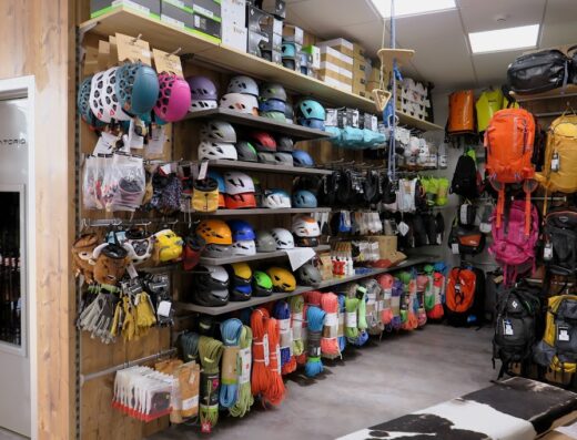 Interior of Valli Sport retail store showcasing helmets, backpacks, climbing ropes, gloves, and other outdoor adventure accessories on shelves.