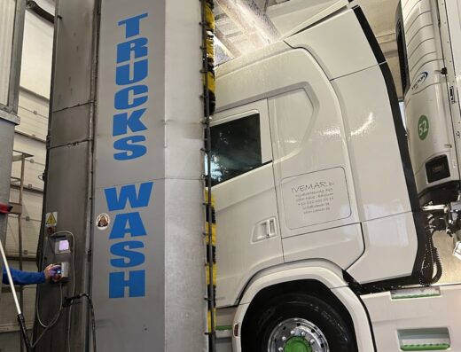 Autolavaggio per camion: Un camion bianco viene lavato in un impianto con la scritta "TRUCKS WASH".