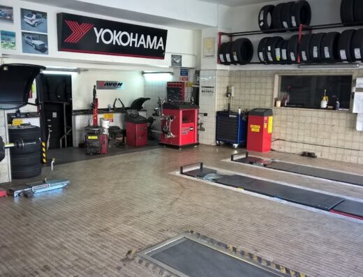 Interno dell'officina Vantaggi Gomme di Vantaggi Stefano & C. Sas con macchinari per la riparazione e sostituzione pneumatici, inclusi equilibratrici e banchi di lavoro, scaffali di gomme Yokohama e Avon.