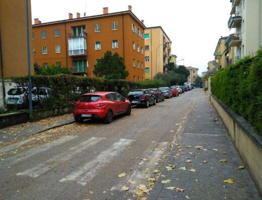 Strada residenziale italiana con auto parcheggiate e foglie autunnali, ideale per esplorare opzioni di viaggio e marketplace di veicoli su Vapama.