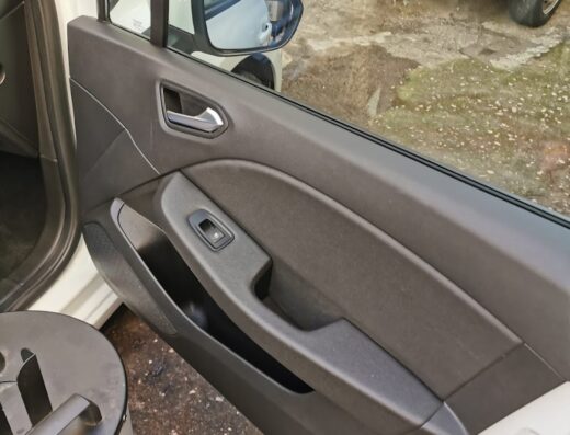 Dettaglio della portiera interna di un'auto bianca durante il servizio di VaporWash, con aspirapolvere visibile. Servizi di pulizia auto.