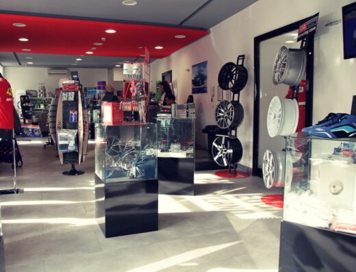 Interno del negozio Vassura Srl, con esposizione di ruote in lega per moto, accessori e abbigliamento tecnico per motociclisti e appassionati di viaggio.