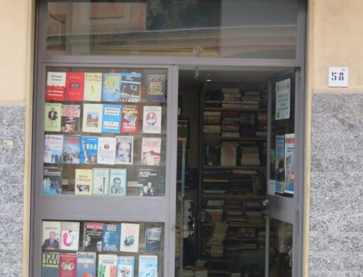 Vetrine di negozio "Vecchi Libri", libreria antiquaria e mercatino dell'usato con esposizione di libri di vario genere e scaffali pieni.