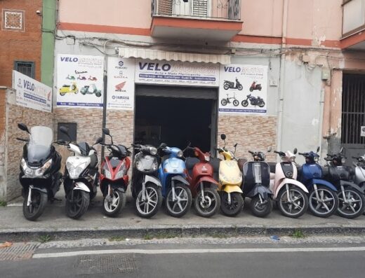Vetrina di Velomotor Velotti Francesco, negozio di ricambi per scooter, moto, vespe e bici, con esposizione di scooter di vari modelli e colori.