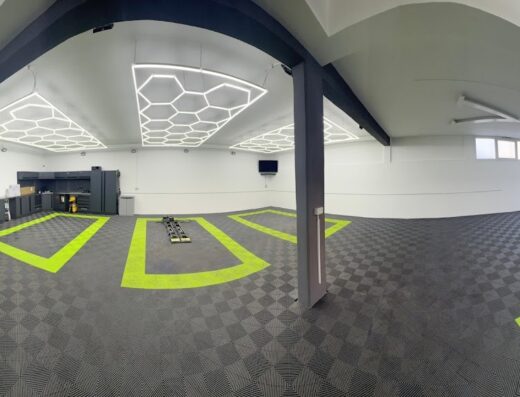 Venditti Luxury Detailing car garage interior with black and gray checkered floor, green car bay outlines, and hexagonal ceiling lights.