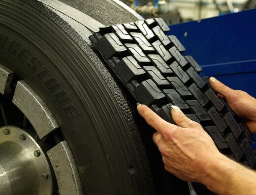 Ricostruzione di pneumatico Bridgestone: dettaglio di un gommista che applica un nuovo battistrada per la ricostruzione di pneumatici.