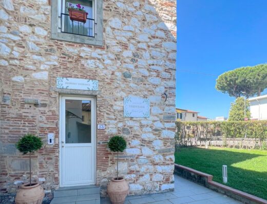 Esterno di VERDERAME Rooms & Suite a Lucca, Italia, con facciata in pietra, ingresso accogliente, e giardino ben curato.