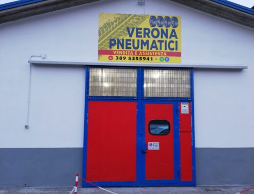 Verona Pneumatici: Facciata del negozio di pneumatici con insegna "Verona Pneumatici" e porta d'ingresso rossa e blu.