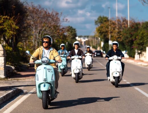 Un gruppo di persone fa un tour in Vespa in Puglia, godendosi il paesaggio. Servizio di noleggio Vespa per un'esperienza di viaggio unica.