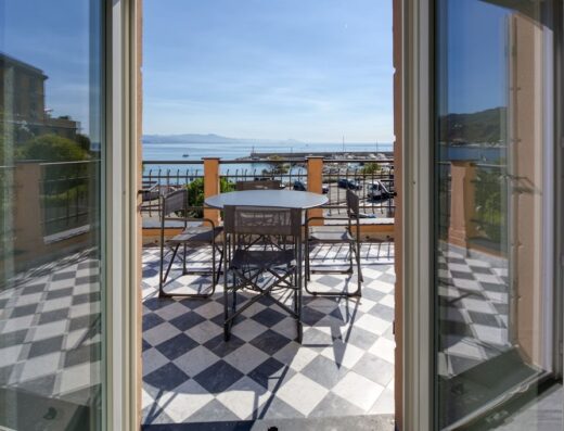 Terrazza panoramica con tavolo e sedie presso Via di Francia Residence Arenzano, con vista sul mare e sul porto turistico.